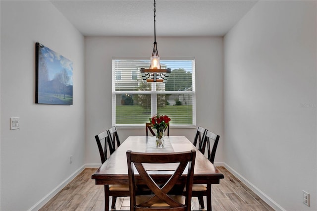 dining space with a textured ceiling, light hardwood / wood-style floors, and a notable chandelier