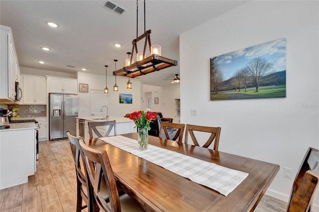 dining room featuring light wood-type flooring, sink, and ceiling fan