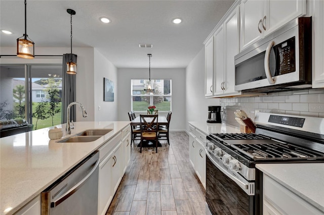 kitchen featuring white cabinetry, pendant lighting, stainless steel appliances, wood-type flooring, and sink