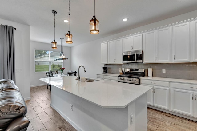 kitchen featuring white cabinets, appliances with stainless steel finishes, decorative light fixtures, and sink