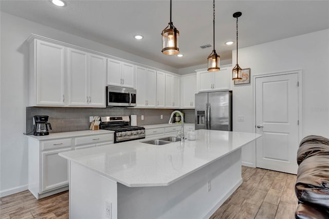 kitchen featuring appliances with stainless steel finishes, white cabinets, sink, and decorative light fixtures