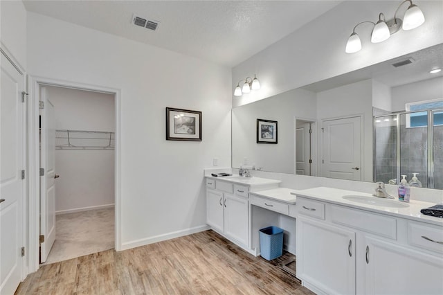 bathroom featuring vanity, a shower with shower door, hardwood / wood-style floors, and a textured ceiling