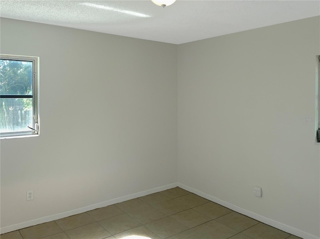 unfurnished room with a textured ceiling and light tile patterned flooring