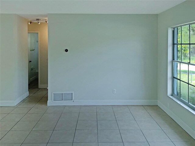 unfurnished room featuring ceiling fan, light tile patterned flooring, and a wealth of natural light