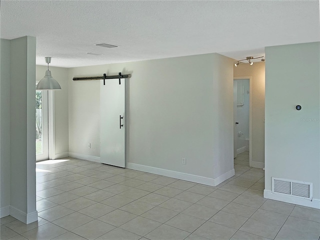 tiled empty room with a textured ceiling and a barn door