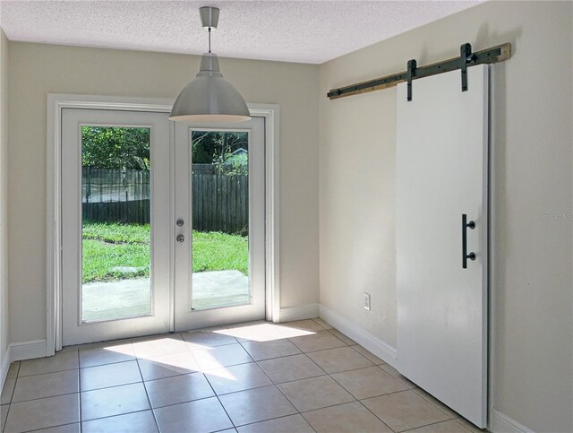 doorway to outside featuring light tile patterned floors, a healthy amount of sunlight, and a barn door