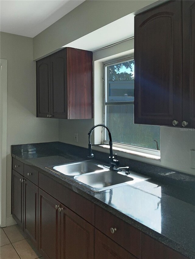 kitchen featuring dark brown cabinetry, light tile patterned floors, and sink