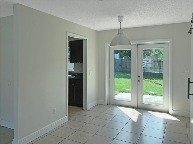 interior space featuring light tile patterned floors, french doors, and a textured ceiling