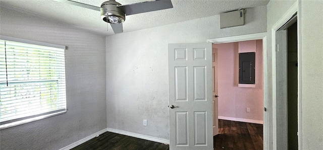 spare room featuring dark wood-type flooring, ceiling fan, and electric panel