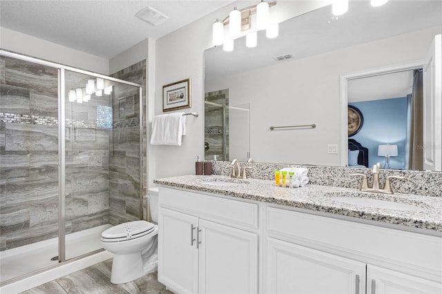 bathroom featuring a textured ceiling, a shower with shower door, vanity, toilet, and hardwood / wood-style flooring