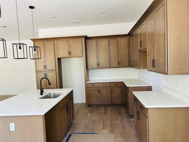 kitchen with a center island with sink, decorative light fixtures, and sink