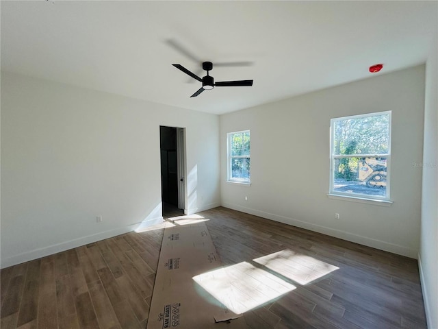 empty room with dark hardwood / wood-style flooring, ceiling fan, and plenty of natural light