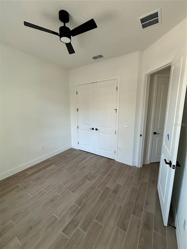 unfurnished bedroom featuring dark hardwood / wood-style flooring, ceiling fan, and a closet