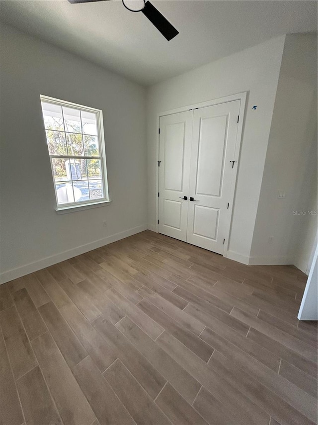 unfurnished bedroom featuring ceiling fan, light hardwood / wood-style floors, and a closet