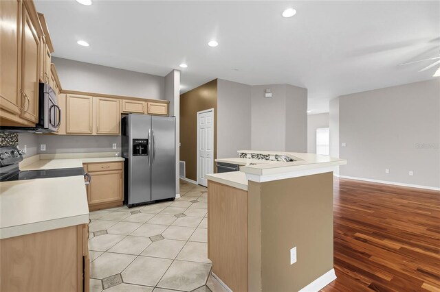 kitchen with a center island, light brown cabinetry, appliances with stainless steel finishes, light hardwood / wood-style floors, and ceiling fan