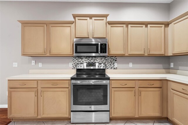 kitchen with appliances with stainless steel finishes, light brown cabinets, backsplash, and light tile patterned floors