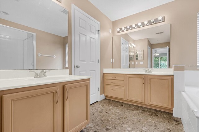 bathroom with vanity and tiled tub