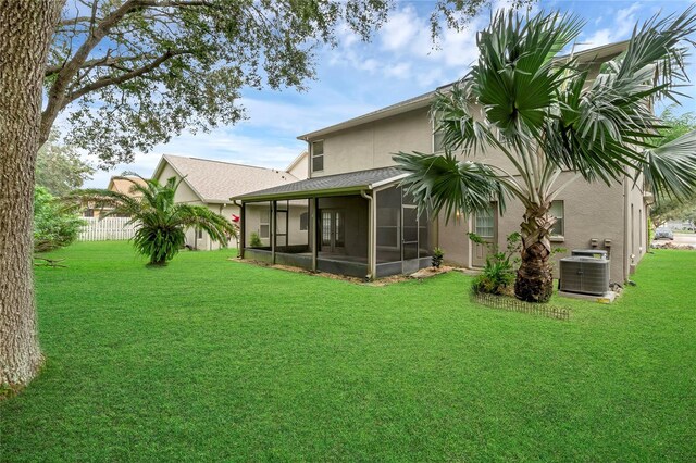 rear view of property with a yard, central air condition unit, and a sunroom