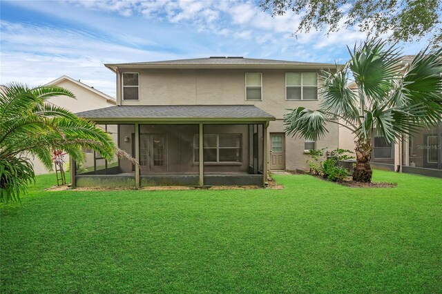 rear view of property with a lawn and a sunroom