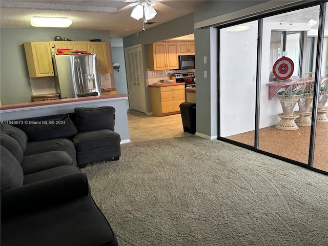 living room featuring ceiling fan, a textured ceiling, and light carpet