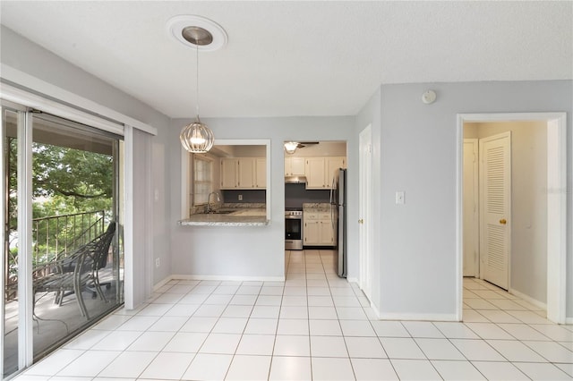 kitchen featuring light tile patterned floors, stainless steel appliances, a textured ceiling, decorative light fixtures, and sink