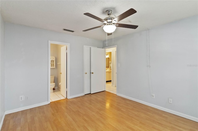 unfurnished bedroom featuring a textured ceiling, light hardwood / wood-style floors, ceiling fan, and ensuite bathroom