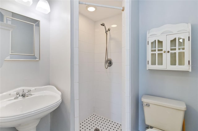 bathroom with a tile shower, sink, and toilet