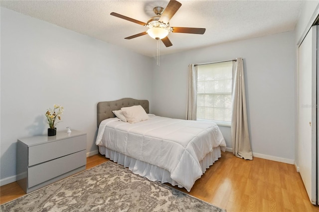 bedroom featuring ceiling fan, a textured ceiling, a closet, and light hardwood / wood-style floors