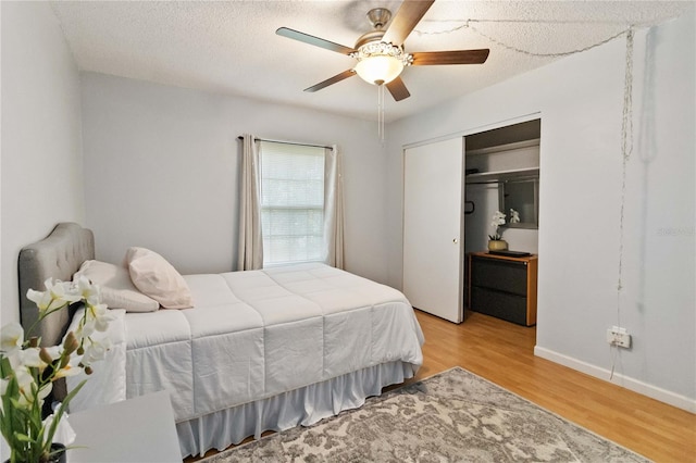 bedroom with ceiling fan, a textured ceiling, light wood-type flooring, and a closet