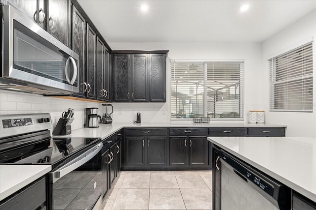 kitchen with appliances with stainless steel finishes, light tile patterned flooring, and backsplash