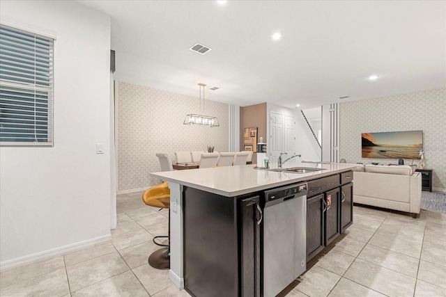 kitchen featuring dishwasher, a breakfast bar area, a center island with sink, sink, and decorative light fixtures