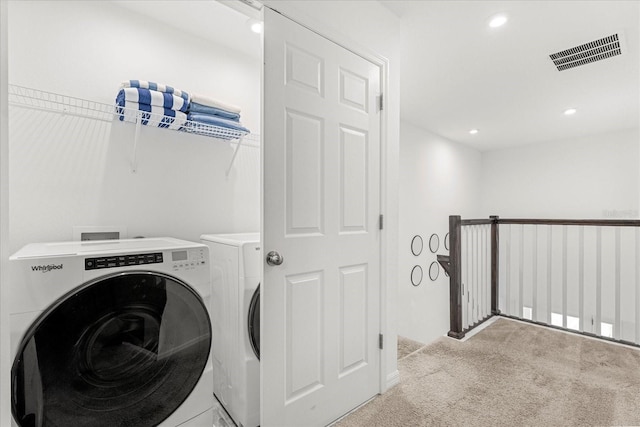 clothes washing area with light carpet and washer and dryer