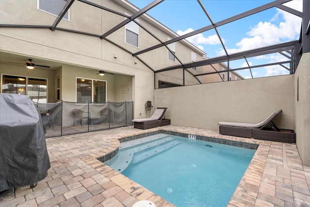 view of pool with ceiling fan, grilling area, glass enclosure, and a patio area