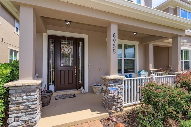 view of exterior entry with a porch and stucco siding