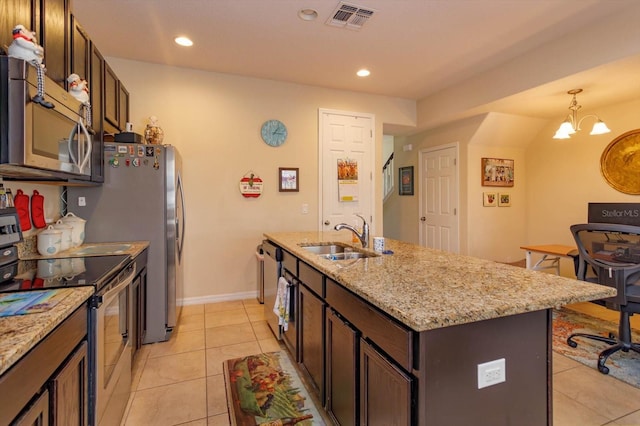 kitchen with appliances with stainless steel finishes, dark brown cabinets, a kitchen island with sink, sink, and a notable chandelier