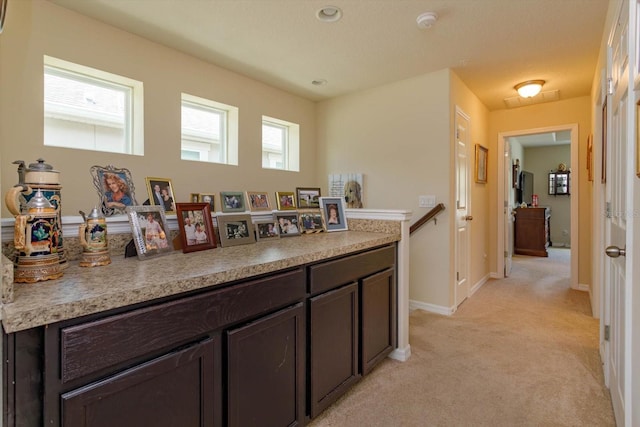 kitchen with dark brown cabinetry and light carpet