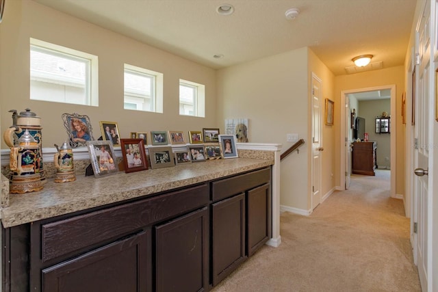 interior space with light countertops, dark brown cabinetry, baseboards, and light carpet