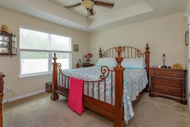 carpeted bedroom with a tray ceiling and ceiling fan