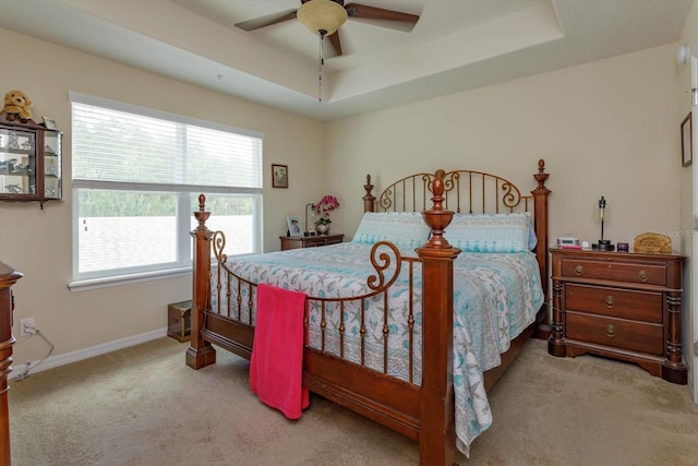 carpeted bedroom with baseboards, ceiling fan, and a raised ceiling