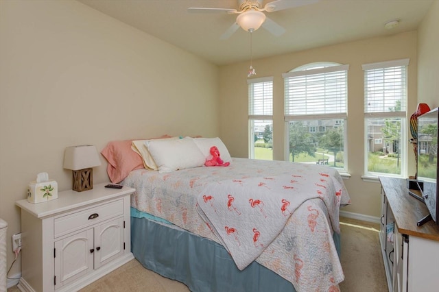 bedroom with a ceiling fan, baseboards, multiple windows, and light colored carpet