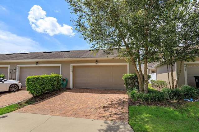 view of front of home with decorative driveway, stucco siding, and a garage