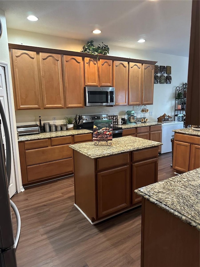 kitchen with appliances with stainless steel finishes, light stone countertops, and dark hardwood / wood-style flooring