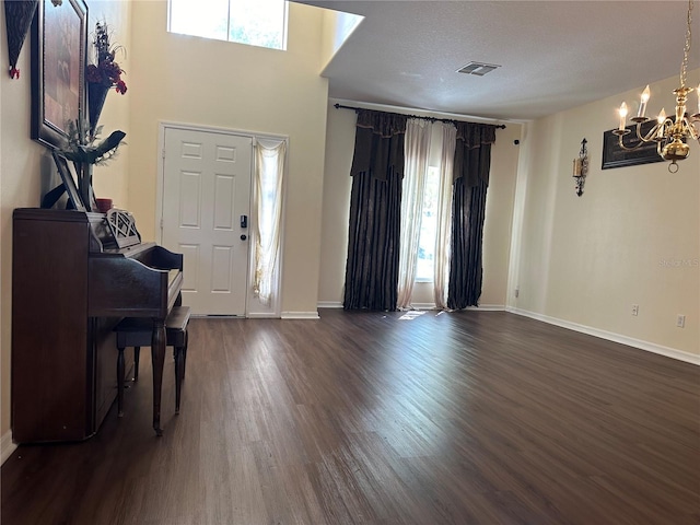 entryway with a textured ceiling, plenty of natural light, dark hardwood / wood-style floors, and a chandelier