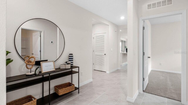 hallway featuring light colored carpet, light tile patterned floors, baseboards, visible vents, and recessed lighting