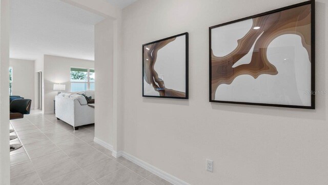 corridor with baseboards and tile patterned flooring