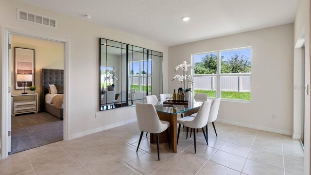 dining space with baseboards, a textured ceiling, visible vents, and light tile patterned floors