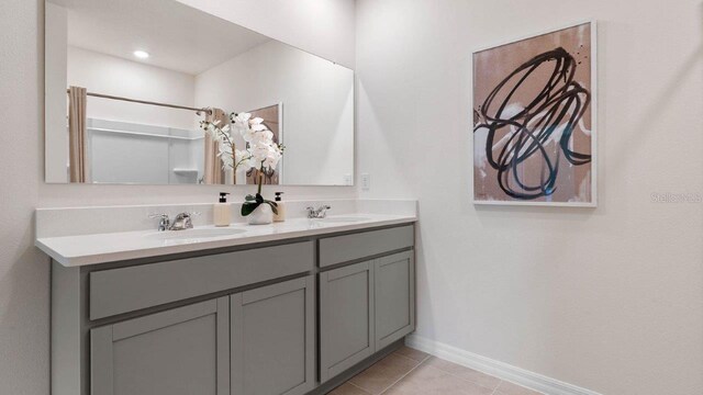 bathroom with tile patterned floors, a sink, double vanity, and baseboards