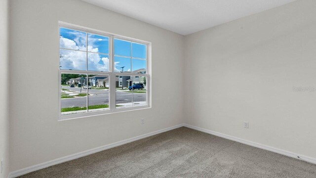 carpeted empty room featuring baseboards