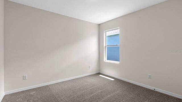 spare room featuring carpet flooring and baseboards