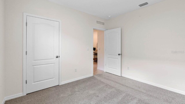 unfurnished bedroom featuring baseboards, visible vents, and carpet